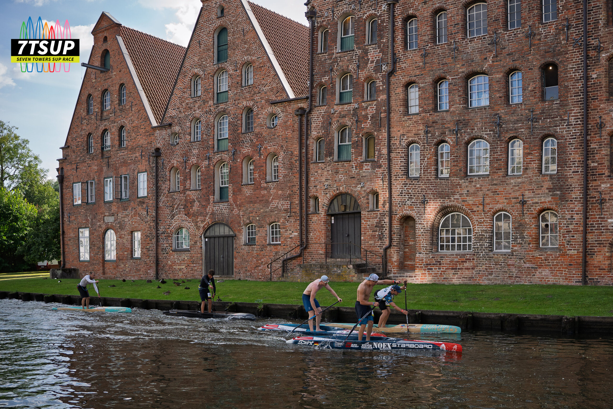 Stand-up-Paddler auf aufblasbaren Boards bei einem Rennen auf ruhigem Wasser.