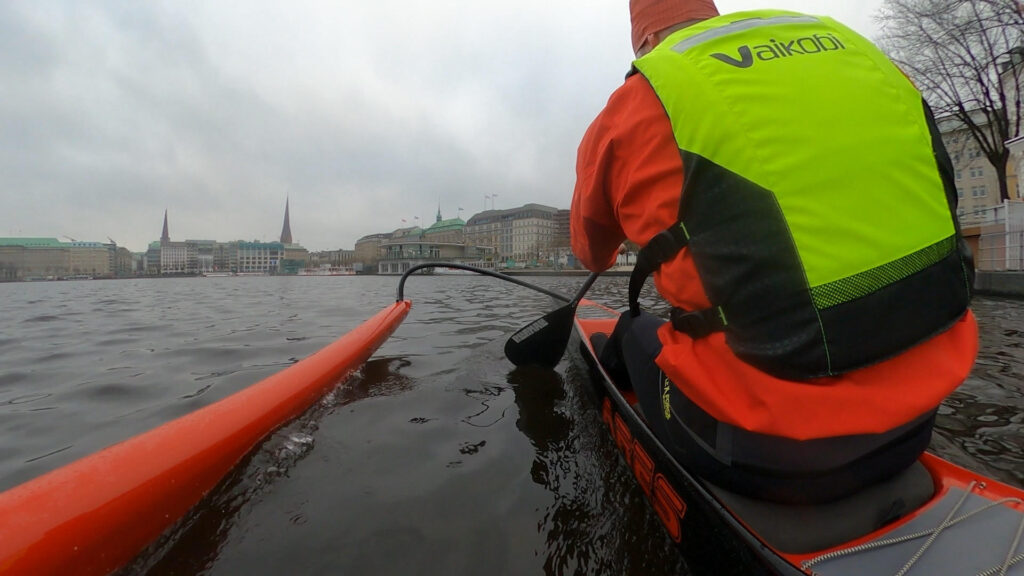 Outrigger-Kanu mit Ausleger auf der Alster, im Hintergrund die Hamburger Innenstadt