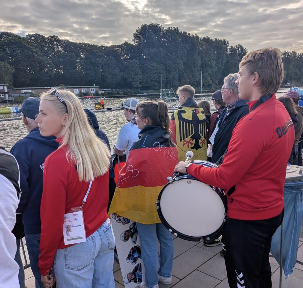 Deutsche Fans mit Trommel, Deutschlandfahne und Bundesadler-Flagge stehen am Rand der Spielfelder an der Regattabahn Duisburg.