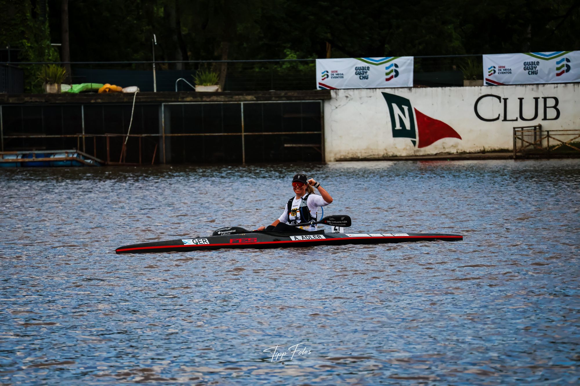 Anja Adler im Kajak auf dem Río Gualeguaychú bei der Kanu-Marathon-WM 2026, im Hintergrund das Bootshaus des Club Náutico